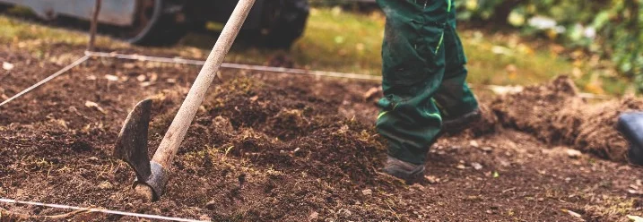 Person bearbeitet Boden mit Hacke